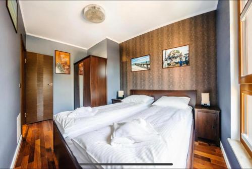 a bedroom with a large bed with white sheets at Urus Home Sopot in Sopot