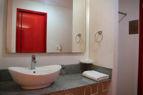 a bathroom with a white sink and a red mirror at Zar Culiacan in Culiacán