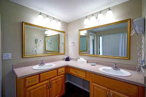 a bathroom with two sinks and two mirrors at Ventura at Boca Raton in Boca Raton