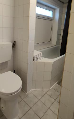 a bathroom with a toilet and a bath tub at Appartementen Dorp & Duin in Egmond aan Zee