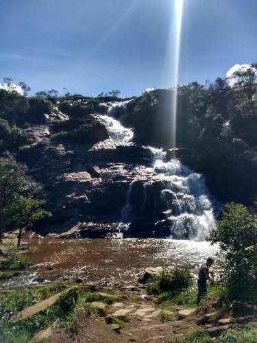 a man standing in front of a waterfall at Pousada do Canto in Rio Acima