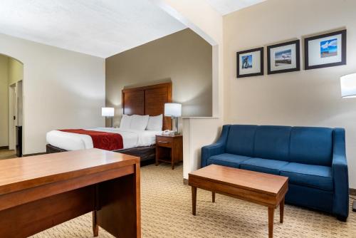 a hotel room with a bed and a blue couch at Comfort Suites Airport in Jacksonville