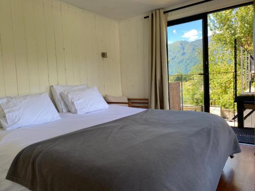 a bedroom with a bed and a large window at French Andes Apart & Chile Campers Rental in Pucón