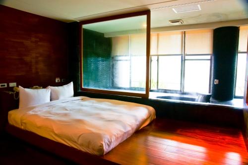 a bed in a room with a large window at Boutique Hot Spring Resort in Xindian