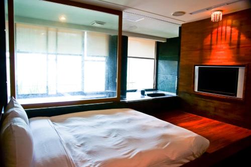 a bedroom with a bed and a tv and windows at Boutique Hot Spring Resort in Xindian