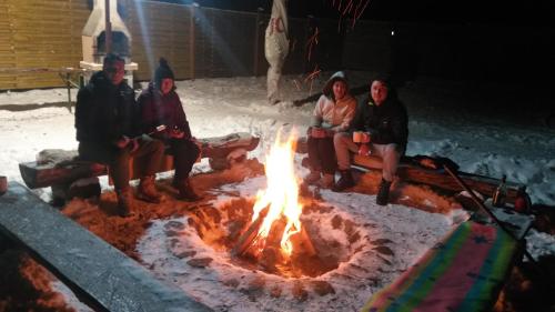 a group of people sitting around a fire at Aroa Mountain in Zărneşti