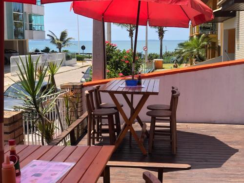 una mesa y sillas con una sombrilla roja en el patio en Quatro Ilhas Beach Hostel, en Bombinhas