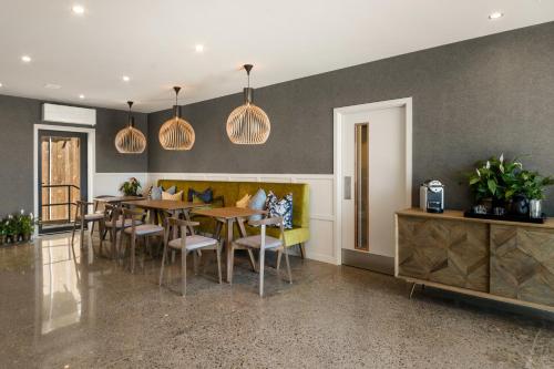 a dining room with tables and chairs and pendant lights at 14th Lane Urban Hotel in Blenheim
