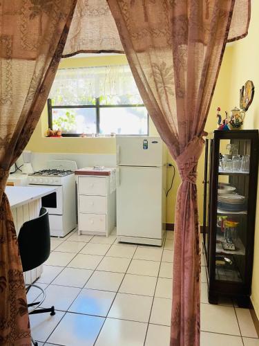 a kitchen with a table and a window with curtains at Villas JABEL TINAMIT in Panajachel