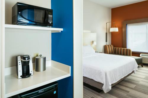 a hotel room with a bed and a tv on a shelf at Holiday Inn Express & Suites - Medford by IHG in Medford