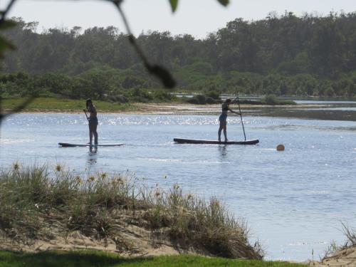 two people are standing on paddle boards in the water at Lakes Entrance Waterfront Cottages with King Beds in Lakes Entrance