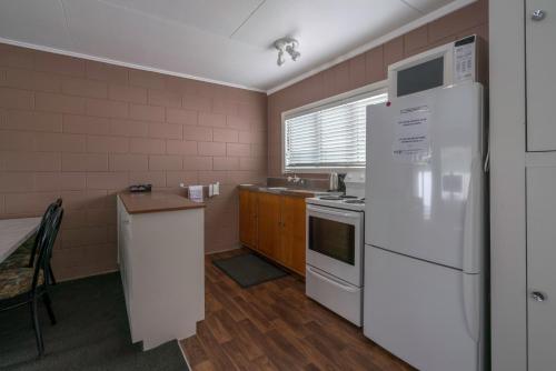 a kitchen with a refrigerator, stove, sink and microwave at Sierra Beachfront Motel in Kaikoura