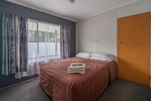 a bedroom with a bed and a large window at Sierra Beachfront Motel in Kaikoura