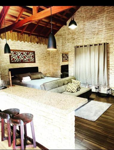 a room with a bed and a bar with two stools at Chalé Villa Magrini in Monte Verde