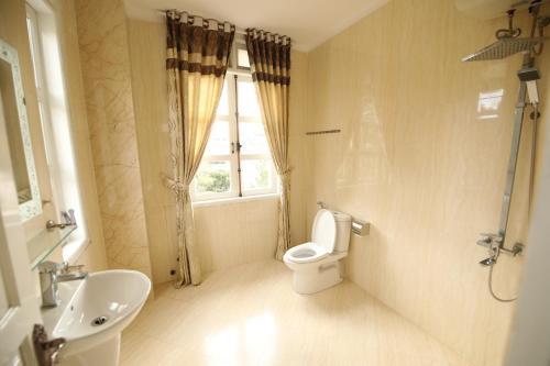 a bathroom with a toilet and a sink and a window at MENTO Villa Đà Lạt in Da Lat