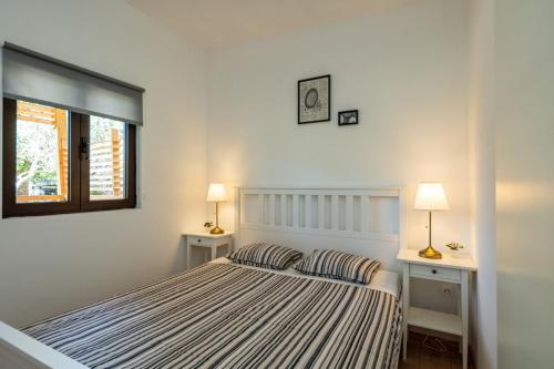 ein weißes Schlafzimmer mit einem Bett und zwei Nachttischen in der Unterkunft Mobile home Rock Samphire 1 in Pakoštane