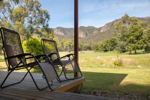 two chairs sitting on a porch looking out at a field at Halls Gap Valley Lodges in Halls Gap