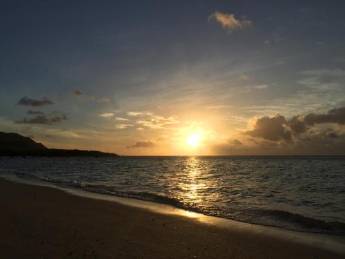 a sunset on the beach with the sun setting at guest house annsea in Ishigaki Island