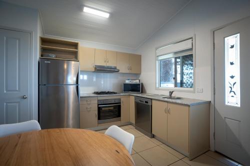 a kitchen with a table and a stainless steel refrigerator at Surf Beach Holiday Park in Kiama