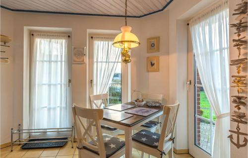 une salle à manger avec une table, des chaises et des fenêtres dans l'établissement Beautiful Apartment In Friedrichskoog, à Friedrichskoog