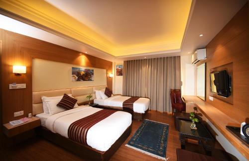 a hotel room with two beds and a television at Hotel Middle Path & Spa in Pokhara