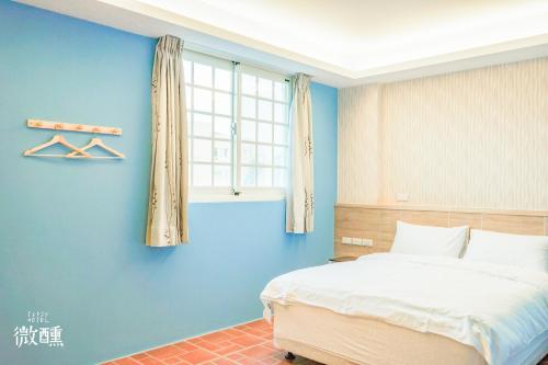 a bedroom with a bed and a blue wall at 金門微醺民宿 Kinmen TipsyHotel B&B in Jincheng