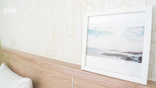a picture frame on a headboard in a bedroom at 金門微醺民宿 Kinmen TipsyHotel B&B in Jincheng