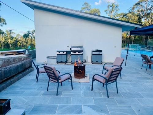 a patio with four chairs and a fire pit at Mountain Valley in Batehaven