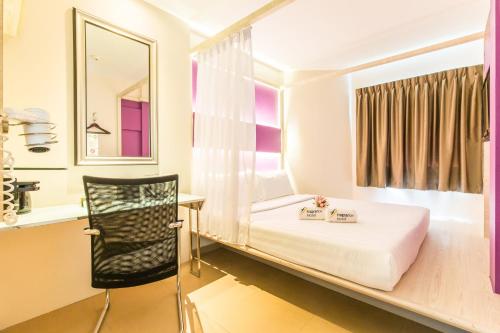 a bedroom with a bed and a desk and a chair at Fragrance Hotel - Viva in Singapore