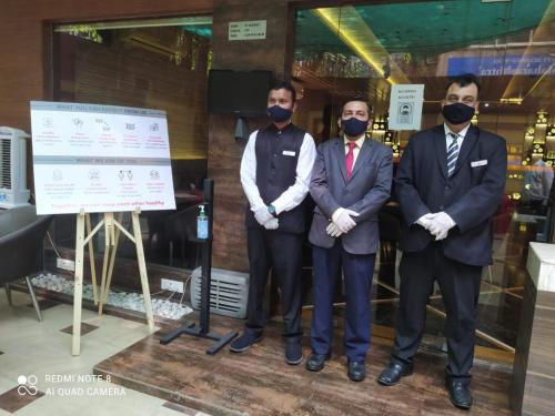 four men wearing masks standing in front of a window at Hotel Plaza in Mumbai