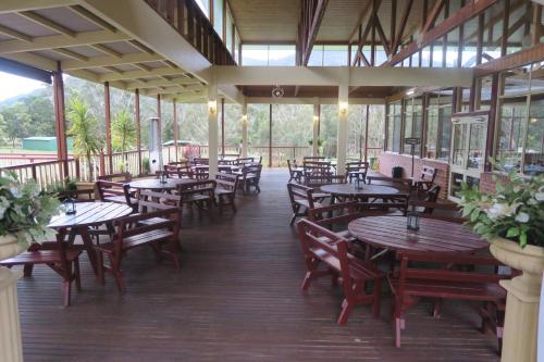 Halls Gap Valley Lodges في هولز غاب: مطعم بطاولات وكراسي خشبية ونوافذ
