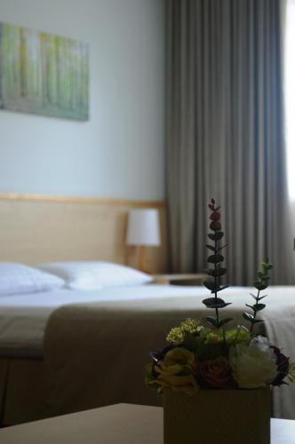 a hotel room with a bed and a vase of flowers at Green Park Hotel Klaipeda in Klaipėda