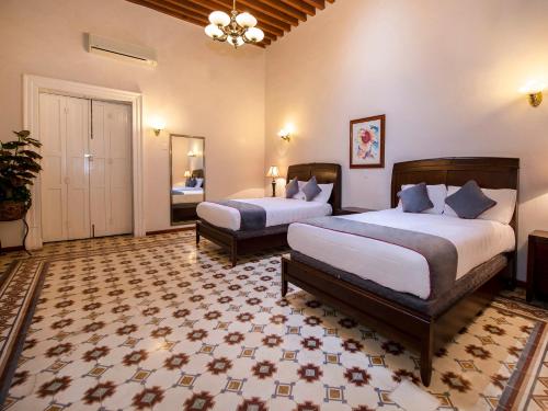 Habitación de hotel con 2 camas y espejo en Hotel Senorial en Querétaro
