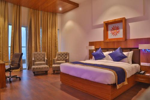 a hotel room with a bed and a desk and chairs at Aveo by Amatra, Gateway to Corbett in Kāshīpur