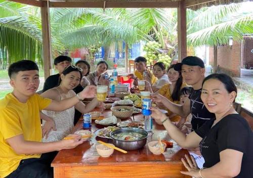 un grupo de personas sentadas alrededor de una mesa comiendo comida en Resort Bao Anh Sunset Beach, en La Gi