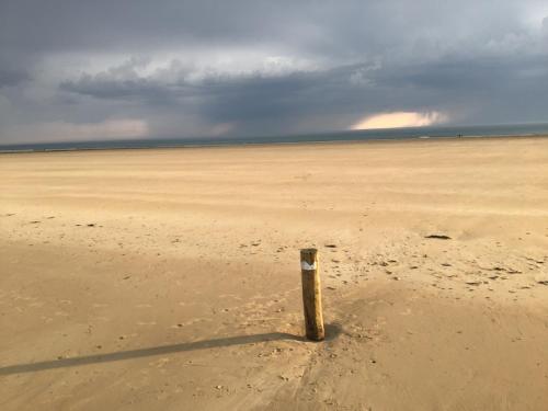 un poste saliendo de la arena en una playa en Aux 13 Arches, en Portbail