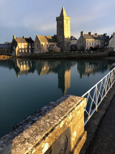 a body of water with a castle in the background at Aux 13 Arches-Logis Hôtel Restaurant in Portbail