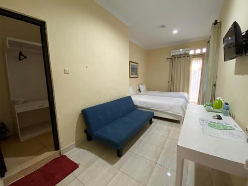 une chambre d'hôtel avec une chaise bleue et un lit dans l'établissement Omah Inap D24 Syariah near Universitas Aisyiah Yogyakarta Mitra RedDoorz, à Sleman