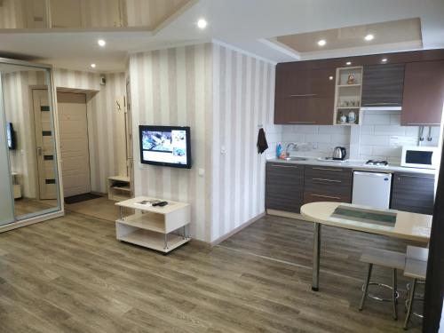 a kitchen with a table and a tv on a wall at Apartment at Kirova (A.Polia) in Dnipro