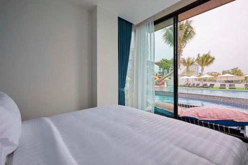 a bedroom with a bed and a view of a pool at Elmas Cha Am Design Hotel in Cha Am