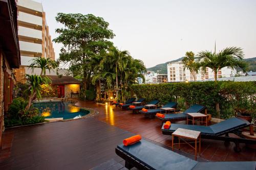 a hotel patio with lounge chairs and a swimming pool at Orchid Garden Hotel Patong in Patong Beach