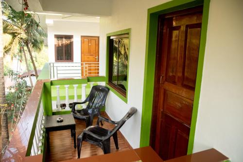 a balcony with two chairs and a table and a door at John's Highland Comfort (Guest House) in Majorda