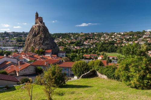 a view of a town and a large rock formation at ibis Styles Le Puy en Velay in Le Puy en Velay