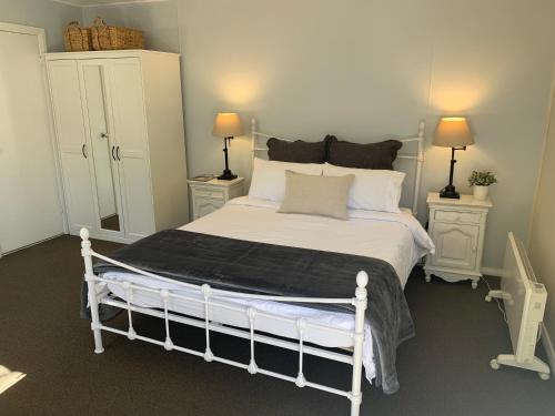 a bedroom with a white bed with two night stands at Aroha Studio in Katoomba