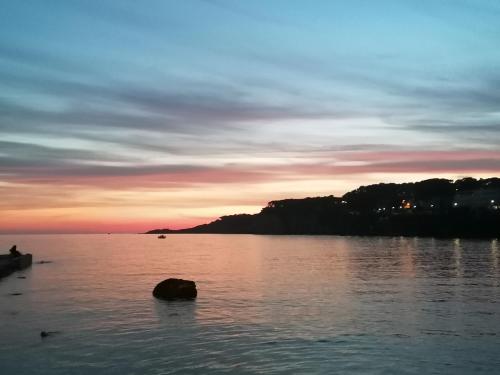 a sunset over a lake with a rock in the water at O Petit Monde in Sanary-sur-Mer
