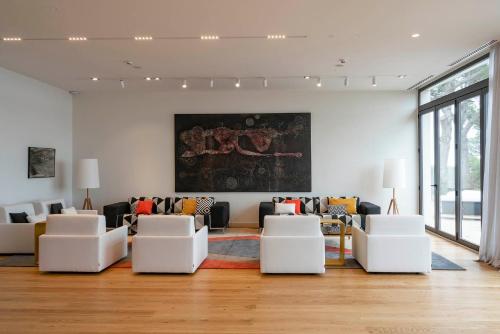 a living room with white chairs and a painting on the wall at Parador de Aiguablava in Begur
