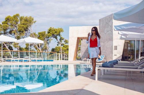 a woman talking on a cell phone next to a pool at D-Resort Šibenik in Šibenik