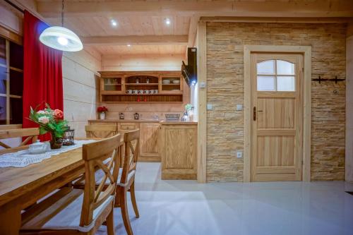 a kitchen with a wooden table and a red curtain at Domek Góralski Symek in Poronin