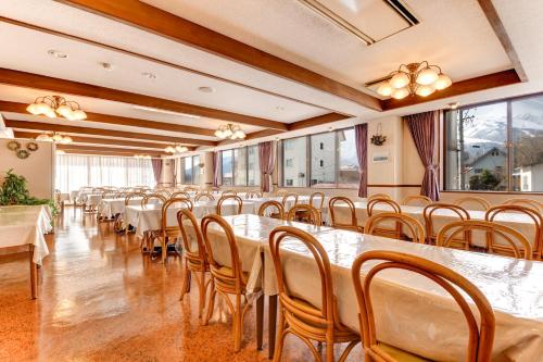 a row of tables and chairs in a room with windows at Hotel La Montagne Furuhata in Hakuba