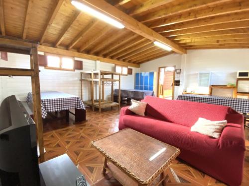 a living room with a red couch and a table at Hostel albergue Paradiso in Hinojedo